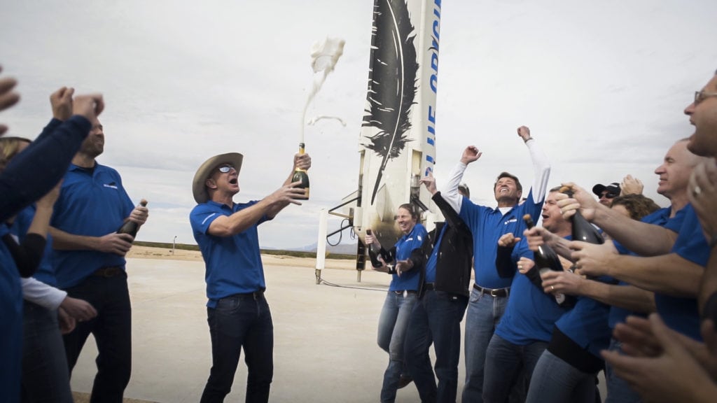 The Blue Origin team celebrates with founder Jeff Bezos at the site of the New Shepard rocket booster landing.