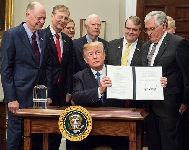 President Donald Trump holds up the Space Policy Directive-1 after signing it, directing NASA to return to the moon, alongside members of the Senate, Congress, NASA, and commercial space companies in the Roosevelt room of the White House in Washington, Monday, Dec. 11, 2017. Photo: NASA/Aubrey Gemignani.