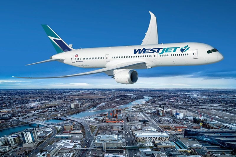 A Boeing 787-9 Dreamliner in WestJet livery flies over a cityscape. Photo: WestJet