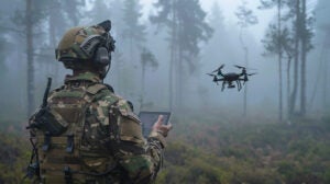 A soldier in camouflage uses a tablet to control drones in a foggy forest, demonstrating modern military equipment. Photo: Xona Space Systems